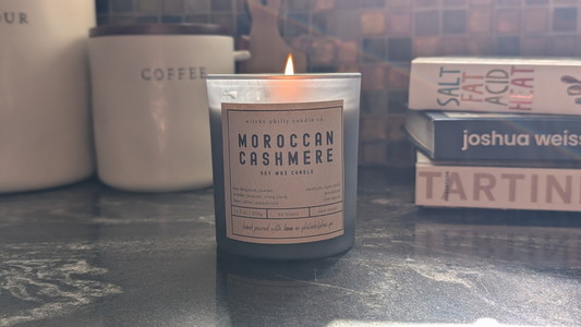 Moroccan Cashmere candle burning on a kitchen counter with cookbooks and kitchen canisters